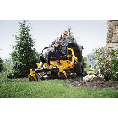 Person operating a yellow riding lawn mower in a garden setting