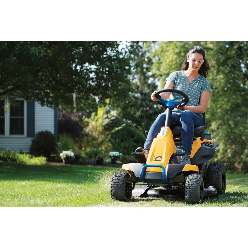 Woman operating a yellow riding lawn mower in a garden.