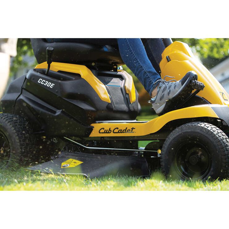 Person operating a Cub Cadet riding lawn mower on grass