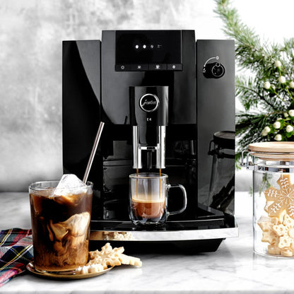 Black coffee machine with a glass of iced coffee and a cup of espresso on a marble surface.
