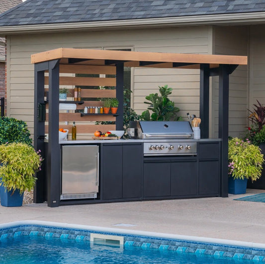 Outdoor kitchen with grill, refrigerator, and bar area next to a pool.