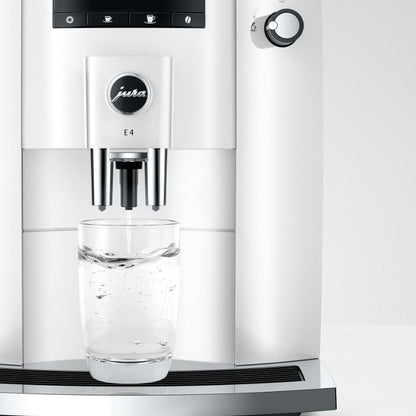 Jura coffee machine dispensing water into a glass on a white background