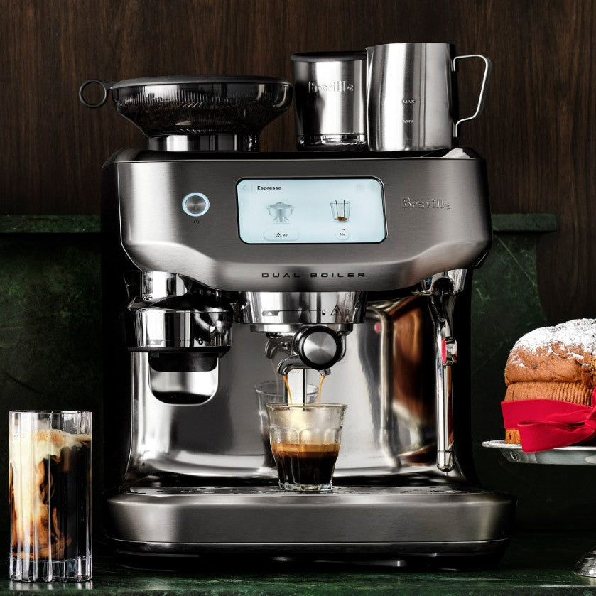 Breville coffee machine with a glass of iced coffee and a cup of espresso on a wooden background