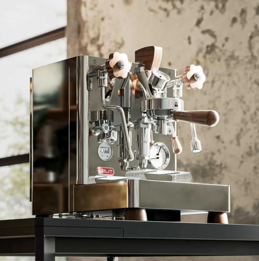 Stainless steel espresso machine on a wooden table with a blurred background