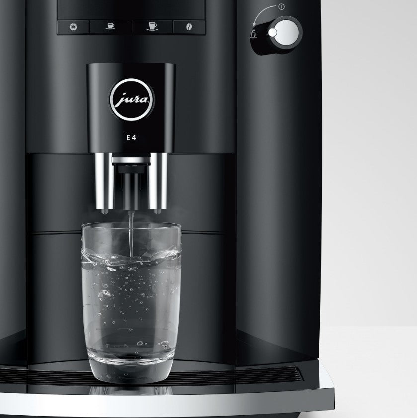 Black coffee machine dispensing water into a glass on a white background