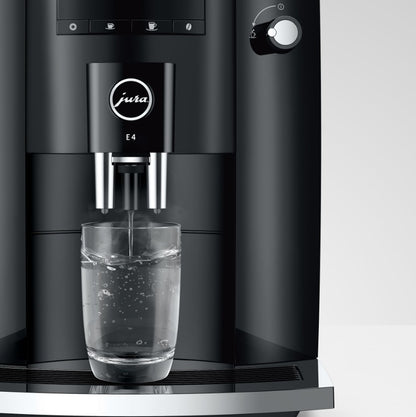 Black coffee machine dispensing water into a glass on a white background