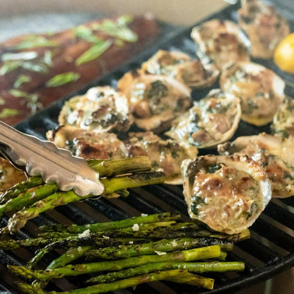 Grilled asparagus and stuffed mushrooms on a grill pan with tongs.