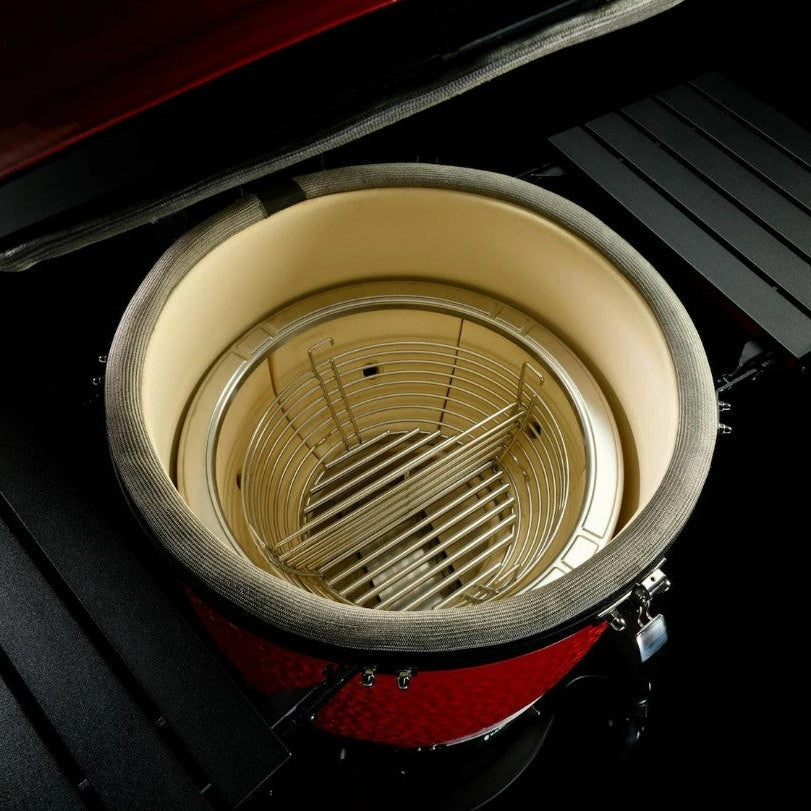 Close-up of a red barbecue grill with a ceramic insert and wire basket.