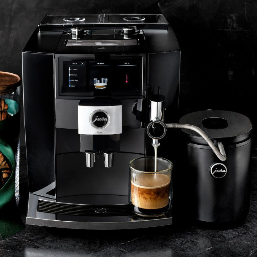 Black coffee machine with a glass of coffee on a dark surface