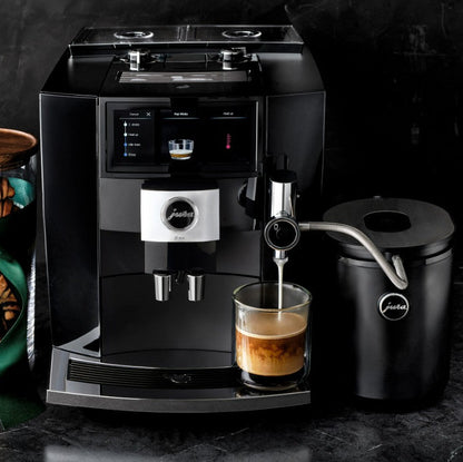 Black coffee machine with a glass of coffee on a dark surface