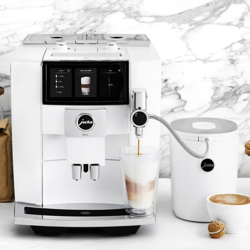 White coffee machine with a glass of coffee and milk on a marble background
