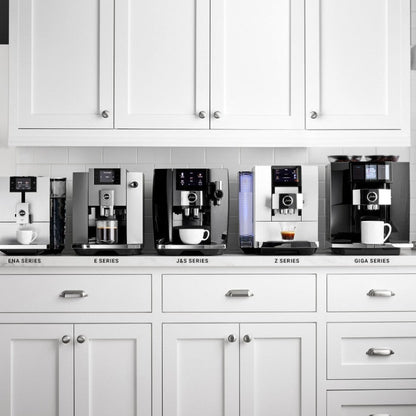Row of coffee machines labeled with different series in a kitchen setting.