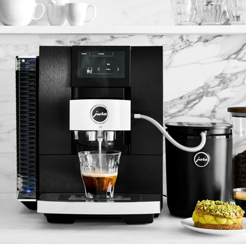 Black coffee machine with a glass of coffee and a container on a marble countertop