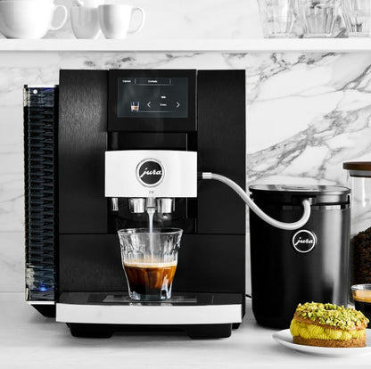 Black coffee machine with a glass of coffee and a container on a marble countertop