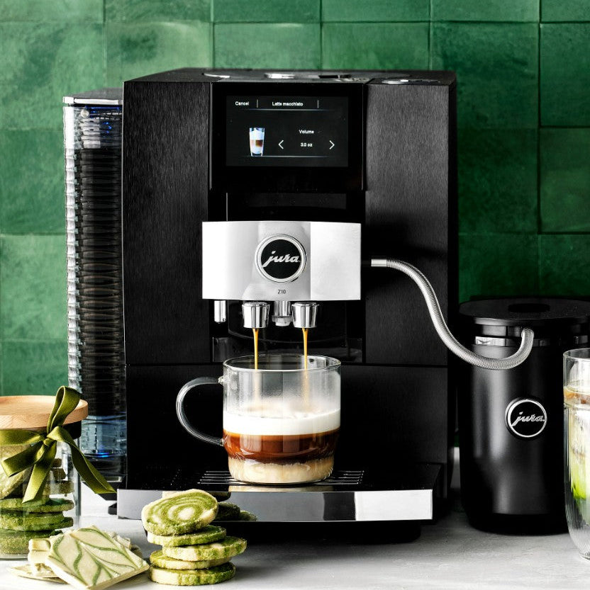 Jura coffee machine brewing a cup of coffee with a green tiled wall in the background