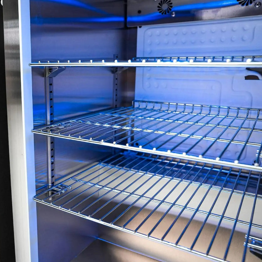 Empty refrigerator with blue interior lighting and metal shelves.