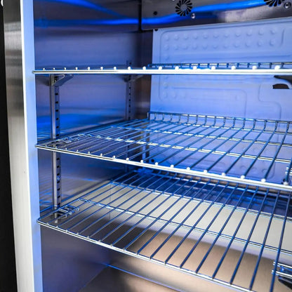 Empty refrigerator with blue interior lighting and metal shelves.