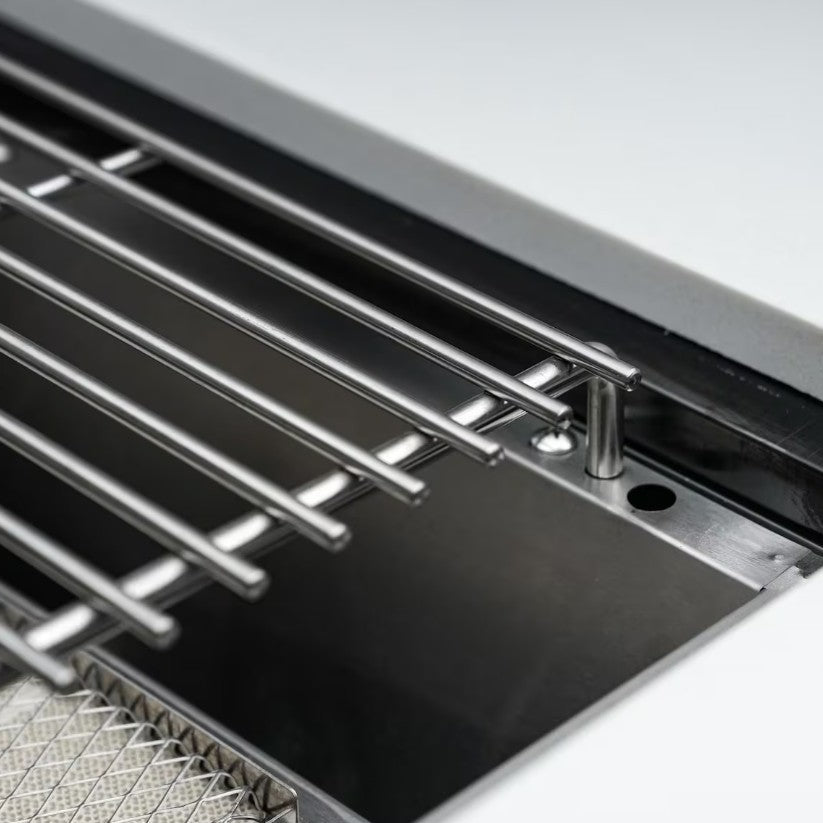 Close-up of a kitchen sink with metal grid and drain.