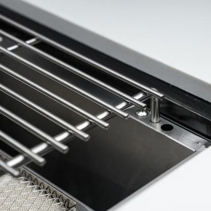 Close-up of a kitchen sink with metal grid and drain.